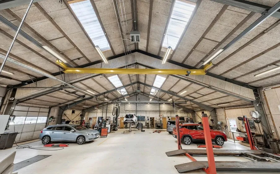 Lejlighed med garage og to biler i en stor industriby. En hvid og en rød bil i garagen og en bil på ophævning.