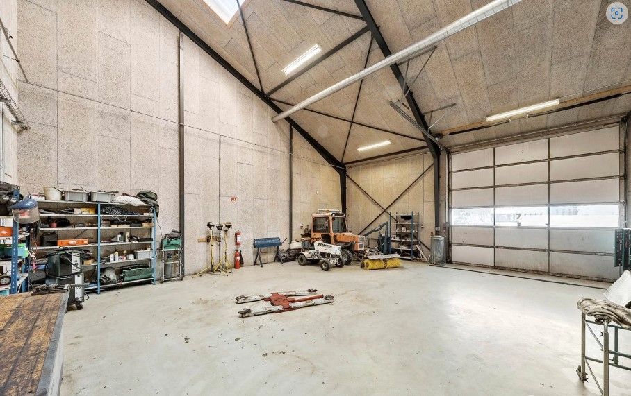 En stor lagerhal med et stort åbent område og flere maskiner og værktøj placeret på hylder