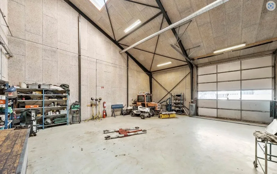 En stor lagerhal med et stort åbent område og flere maskiner og værktøj placeret på hylder