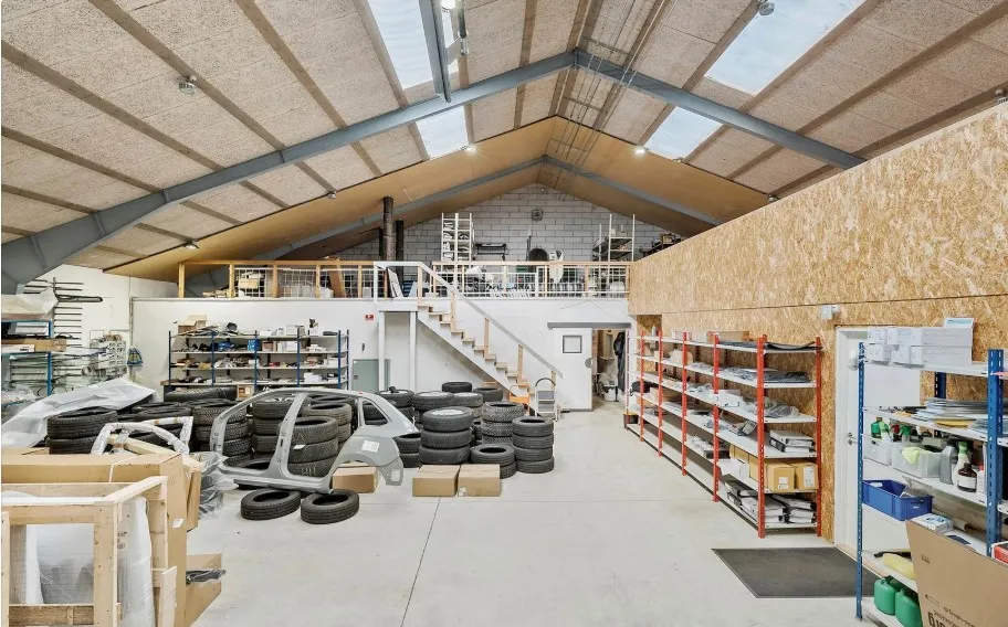 Industribygning med garage, lager og kontorlokaler i et rum, med trappe og vinduesparti, fuld af materialer og værktøj