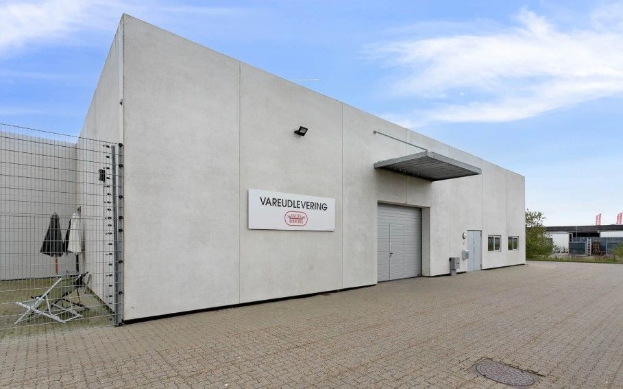 Hjørnebygning med skiltet Vareudlevering og to store garageporte på Dandyvej 5A i Vejle.