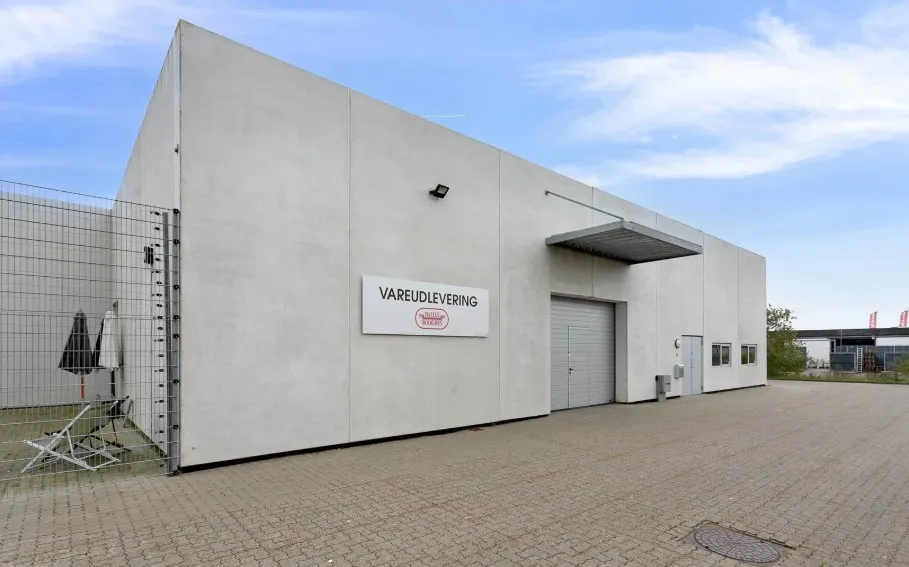 Hjørnebygning med skiltet Vareudlevering og to store garageporte på Dandyvej 5A i Vejle.