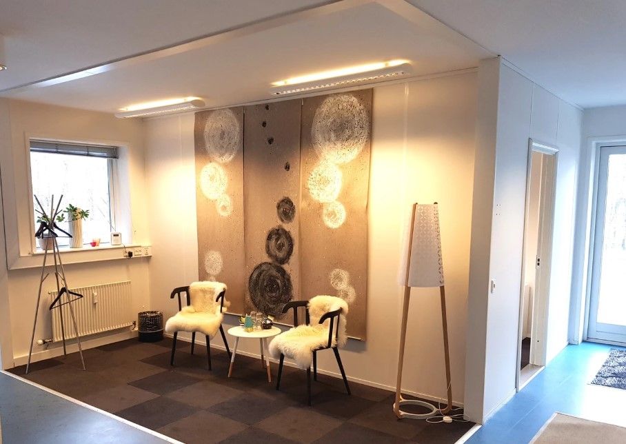 Kontorlokaler med hvide vægge og møbler, der er pyntet med kunstværker og tæpper