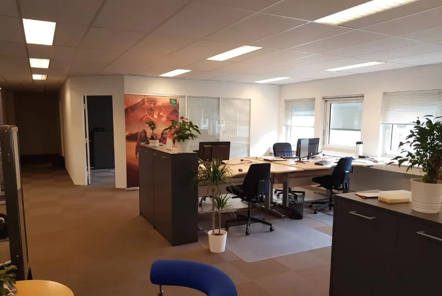 Kontorlokale med lyse gulvvelegnende gulvvelegnende gulv og højt loft, to store borde med computere og to små borde med