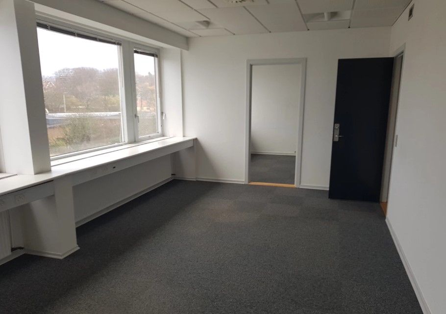 Ledig kontor i Esbjerg med vinduer og døre. Ingen møbler. Sort dør og spejl.