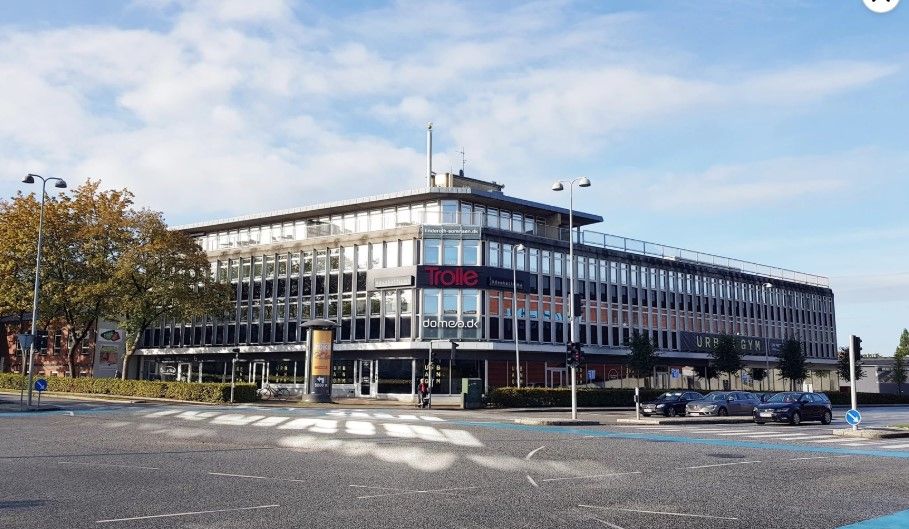 Kontorbygning med glasvinduer og skilte med navnet Trolle på facaden og forside.