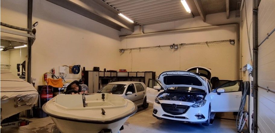 Bilværksted med åbne biler og en person, der arbejder i en af bilerne