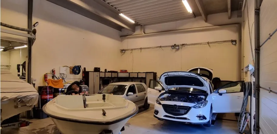 Bilværksted med åbne biler og en person, der arbejder i en af bilerne