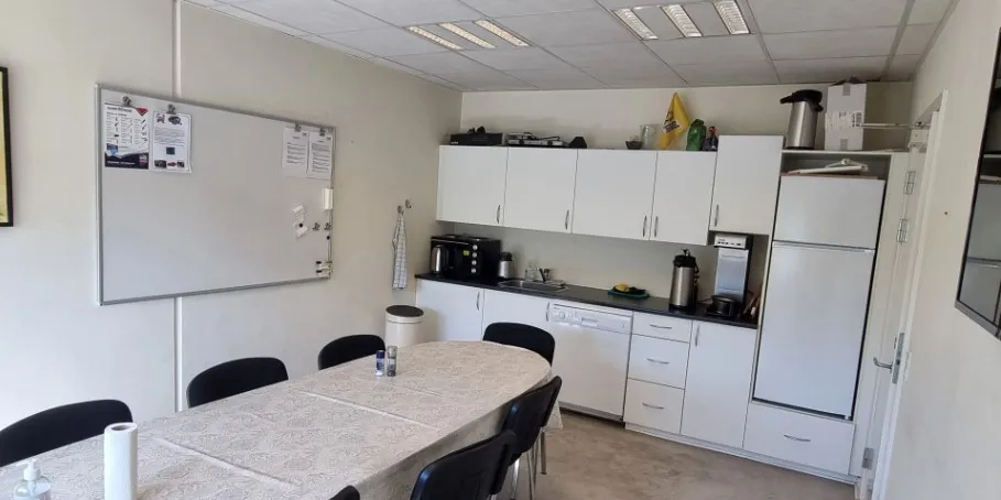 Lokale med bord, stole, køleskab, mikroovn, skrivebræt og udstyr som skraldespand og kaffemaskine.