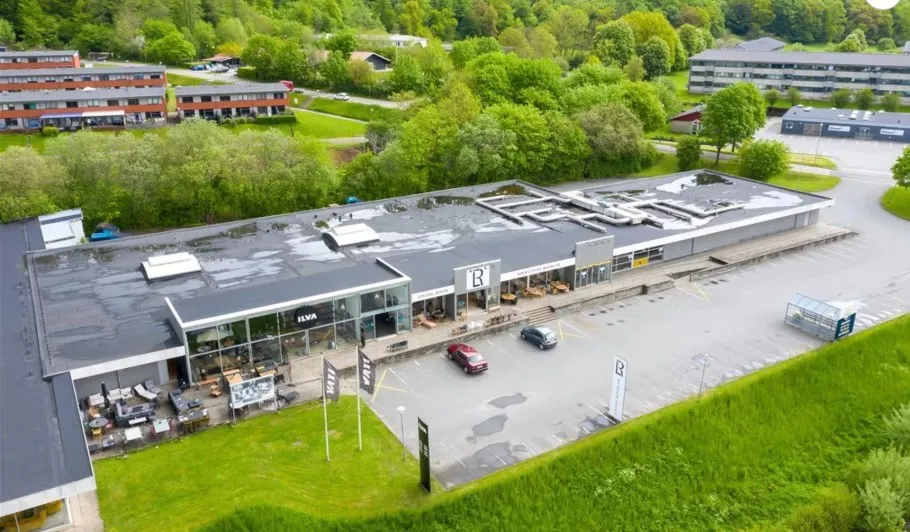 Bygning med parkeringsplads og biler og mærke R på facaden og skilte med mærket R