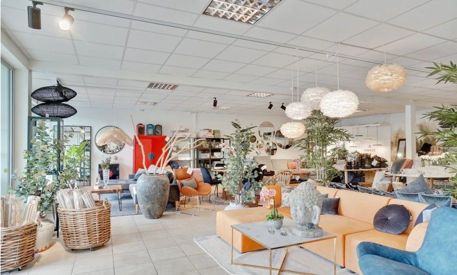 En hyggeligt indrettet stue med lyse møbler og hyggelige dekorationer, hvor der er et stort sofa-sæt og et stol-sæt