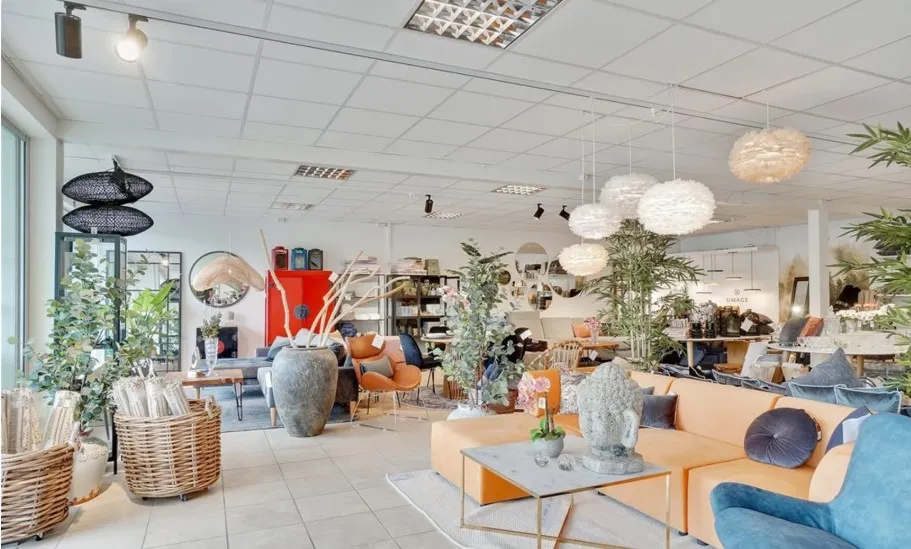 En hyggeligt indrettet stue med lyse møbler og hyggelige dekorationer, hvor der er et stort sofa-sæt og et stol-sæt