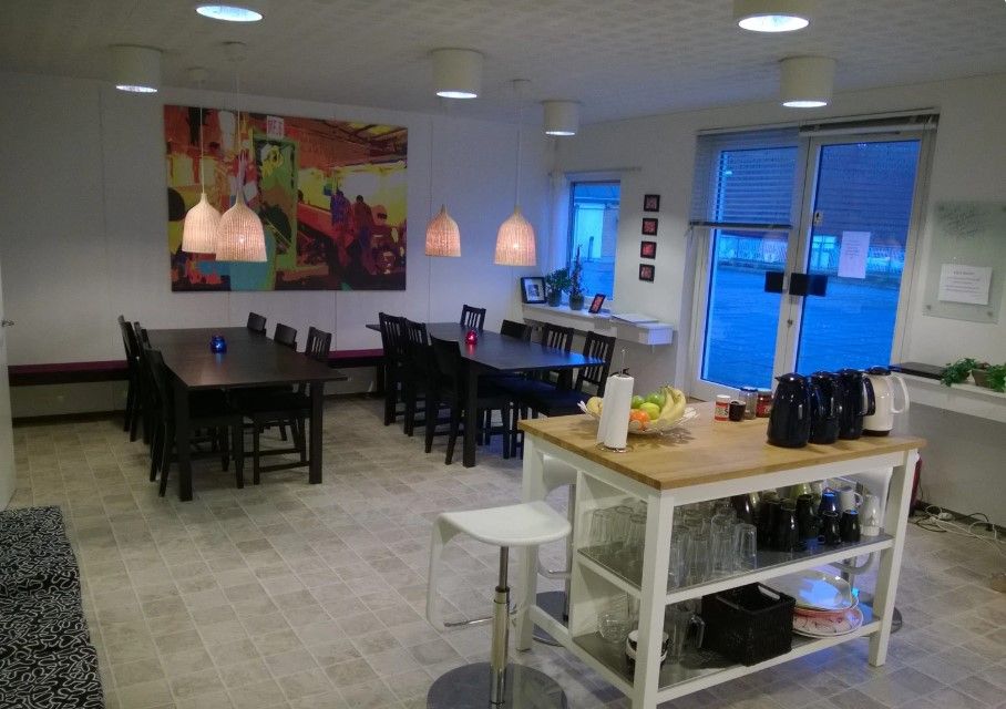 Bord med frugt, kaffemaskine, og glas i en lys stue med kunstværk og moderne møbler