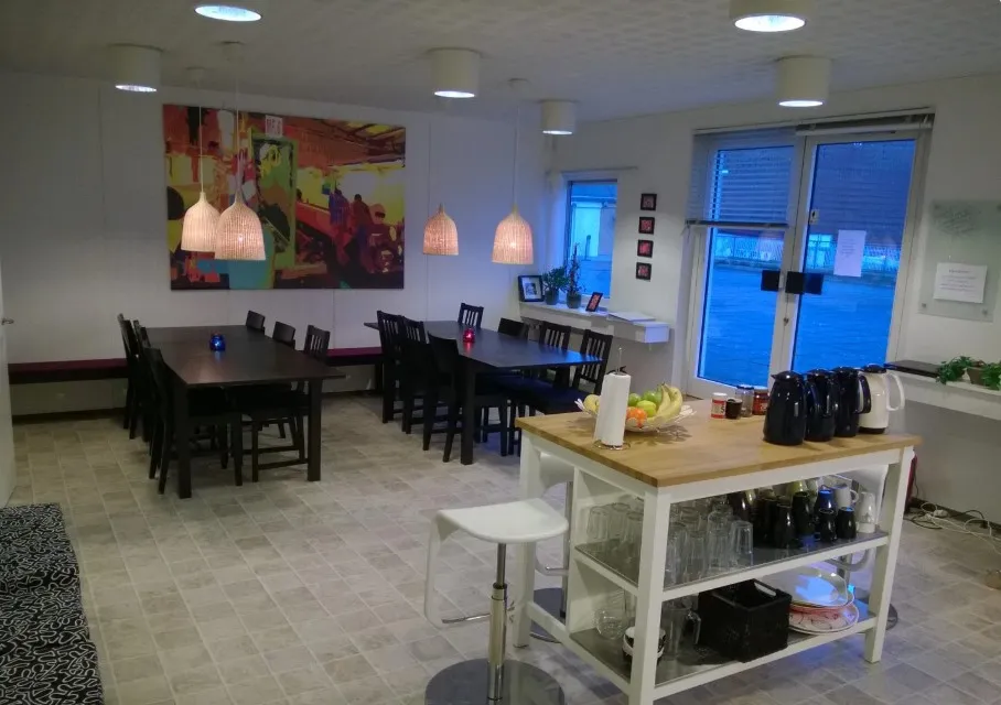 Bord med frugt, kaffemaskine, og glas i en lys stue med kunstværk og moderne møbler