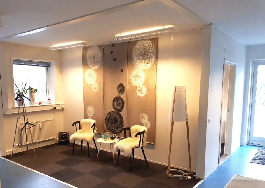 Køkken med møbler og lysekroner. Væg med maleri og møbler samt plante i vindueskarmen.