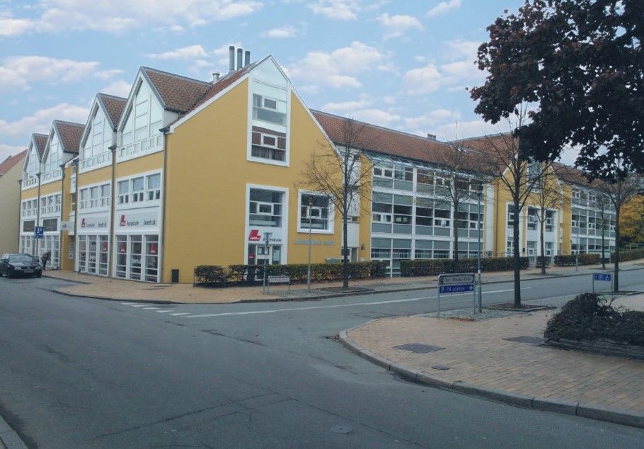 Kontorby i Sct. Nicolai Gade 5 i Aabenraa med gule vægge og store vinduer. Et parkerede bil og grønne buske langs siderne