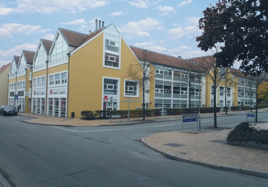 Kontorby i Sct. Nicolai Gade 5 i Aabenraa med gule vægge og store vinduer. Et parkerede bil og grønne buske langs siderne