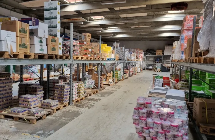 Lager med forskellige produkter og kasser, herunder kartoner med mærket Golden. Kasser med mærker som Nido og Ardagh Tea.
