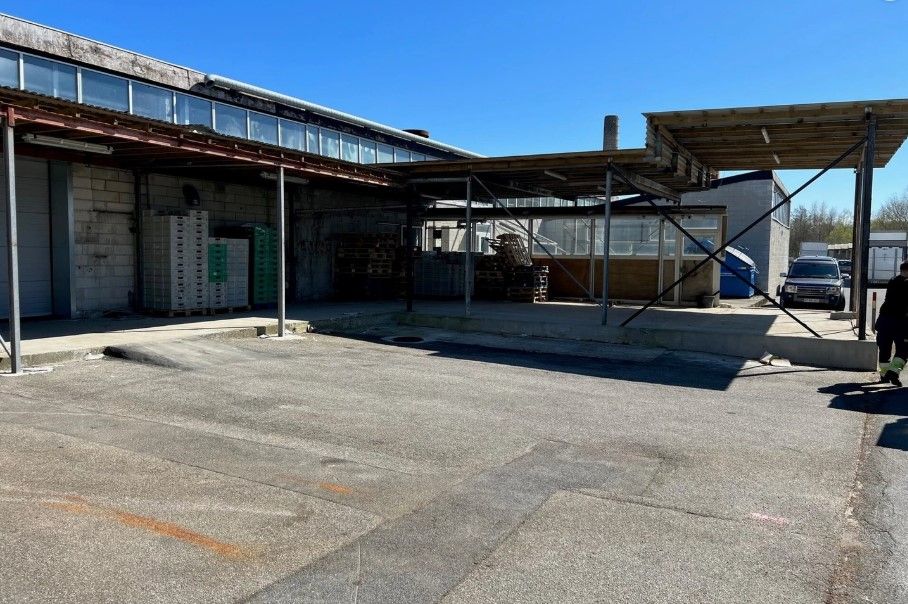 En stor industribygning med et åbent område og en person, der går langs siden af bygningen