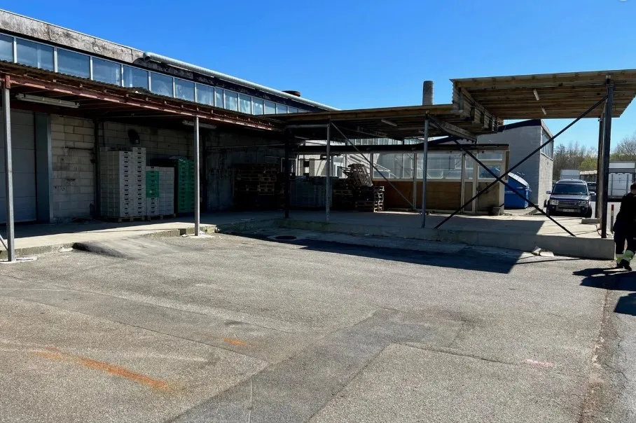 En stor industribygning med et åbent område og en person, der går langs siden af bygningen