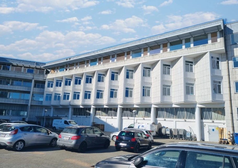 Kontorlokale med parkeringsplads og solrig himmel med skyer i Esbjerg