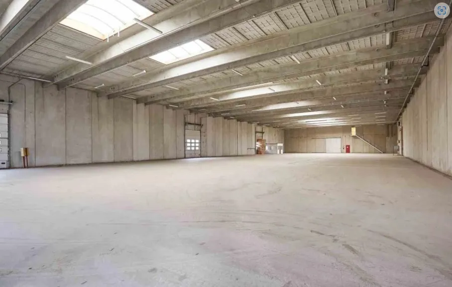 Lagerhal med højt til loftet, lyseskygger og åbne døre til indgangsmuligheder