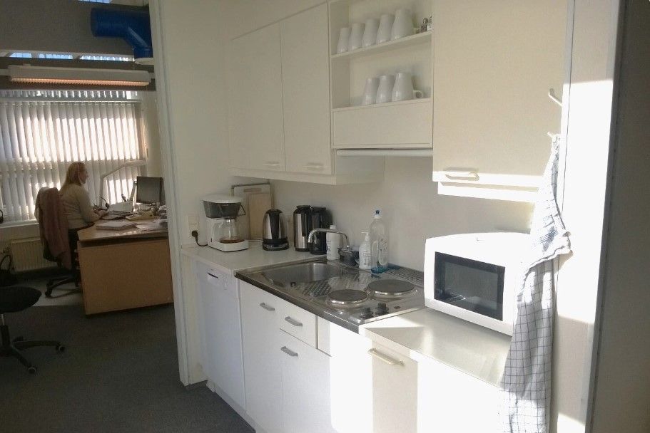 et lyse og moderne kontor med hvide køkkenskabe, en komfur og en mikroovn