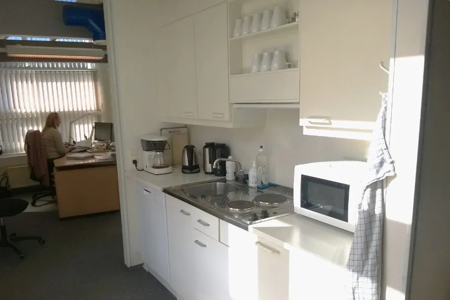 et lyse og moderne kontor med hvide køkkenskabe, en komfur og en mikroovn