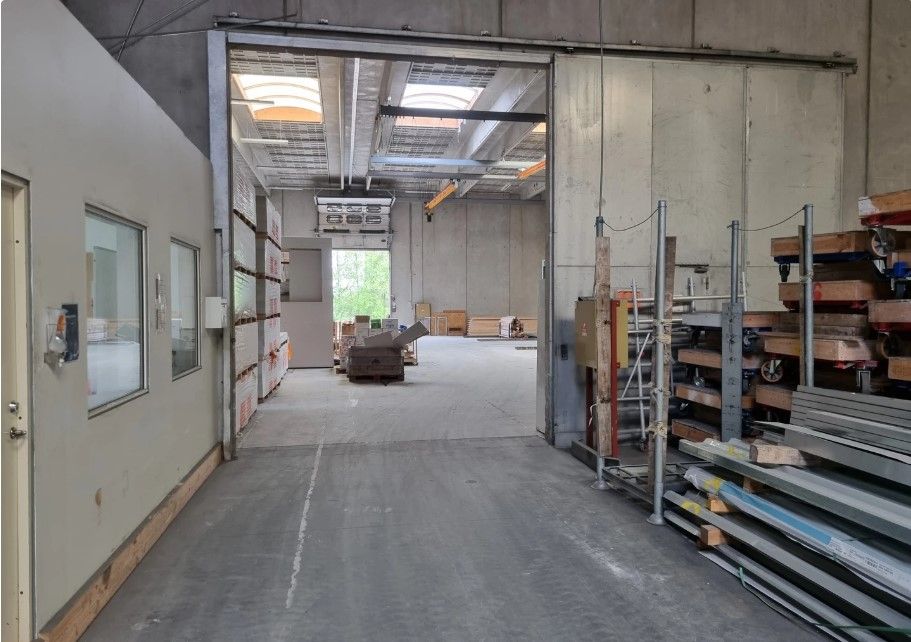 Lager med kontor på 2.500 m2. Lagerhallen er højloftet og ren. Der er en stor åbning til venstre med vinduer og klimaanlæg.