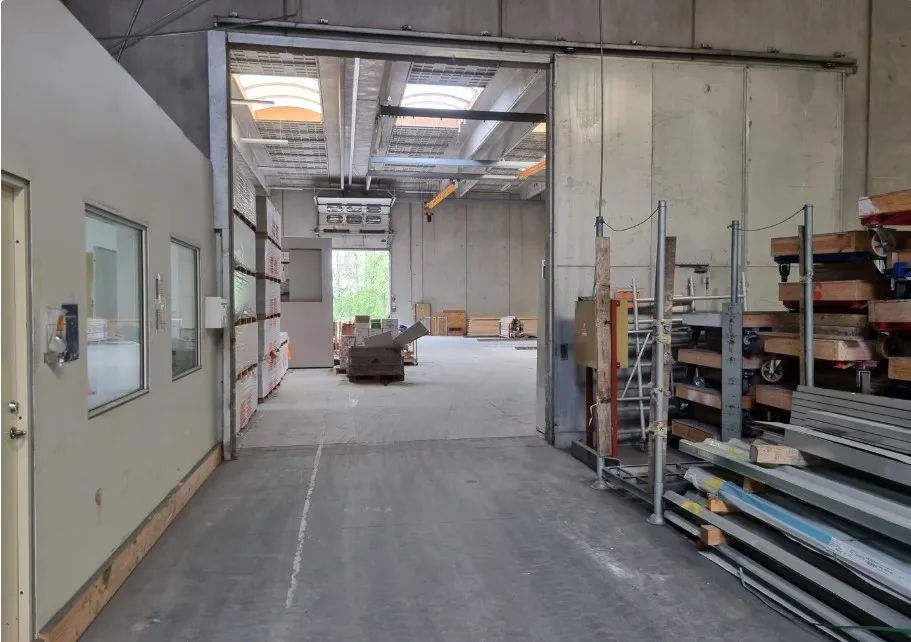 Lager med kontor på 2.500 m2. Lagerhallen er højloftet og ren. Der er en stor åbning til venstre med vinduer og klimaanlæg.