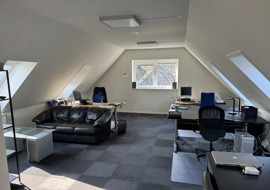 Kontor med skriveborde og computere, skrivebordslamper og vinduer i loftet