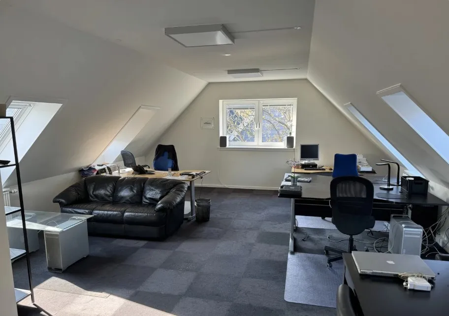 Kontor med skriveborde og computere, skrivebordslamper og vinduer i loftet