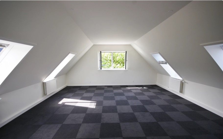 Et tomt kontor med krydsfinerbelagt loft og vægge samt gulvtæppe med sort og grå kryds.