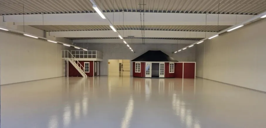 En stor hall med hvide vægge, en stor hvid gulv og to små røde hus i højre side af hall.