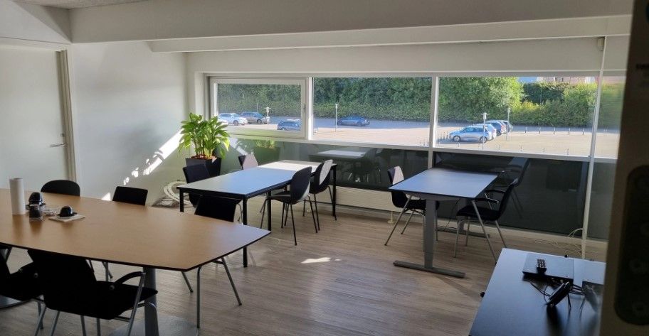 En stor mødelokale med moderne møbler og et smukt udsigtsvindue til parkeringspladsen med biler i baggrunden