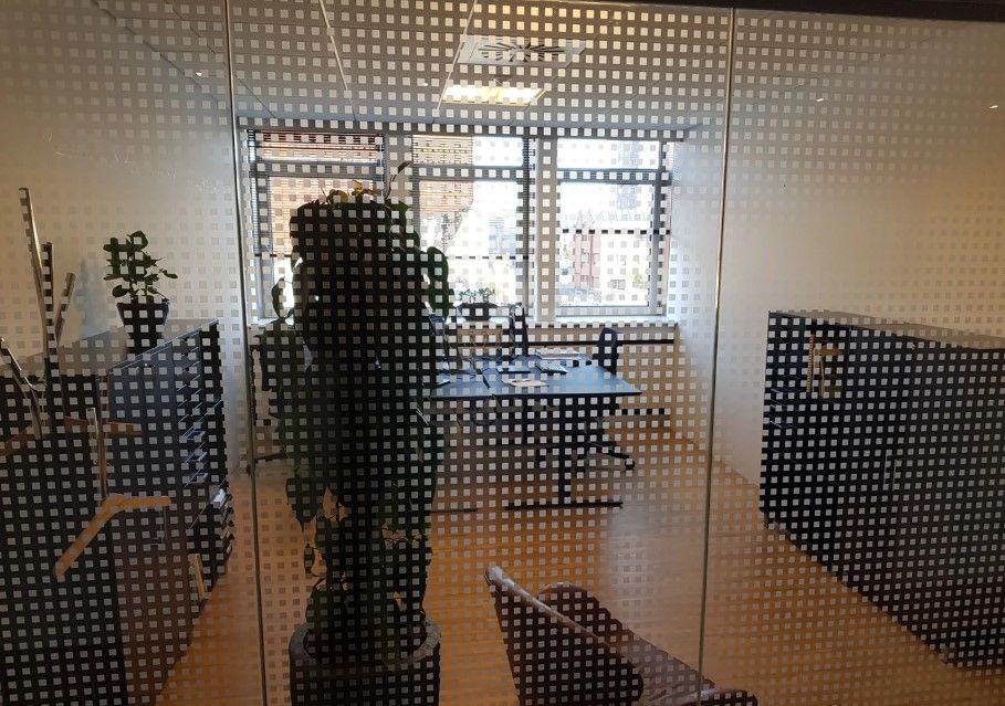 Kontor med møbler og grønne planter på gulvet og bord med bøger og glas på gulvet.