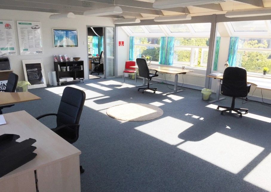 Kontor med lyse vinduer, moderne møbler, og solskin strømmer ind for at skabe et varmt og indbydende arbejdsmiljø