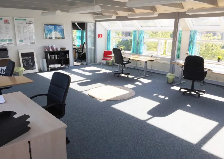 Kontor med lyse vinduer, moderne møbler, og solskin strømmer ind for at skabe et varmt og indbydende arbejdsmiljø