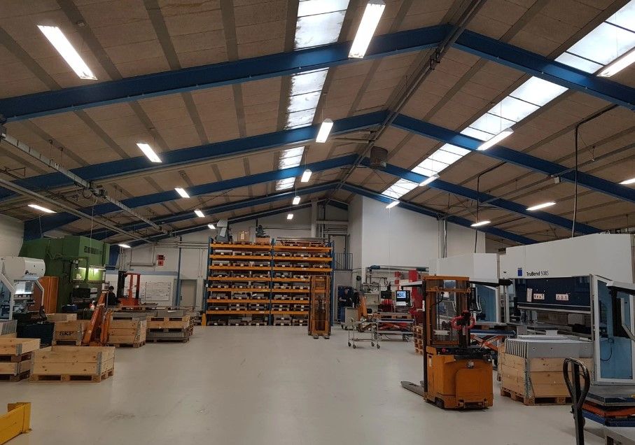 Forretningslokaler med lager, maskiner og køretøjer, sammen med store lagerhylder og højloftede rum