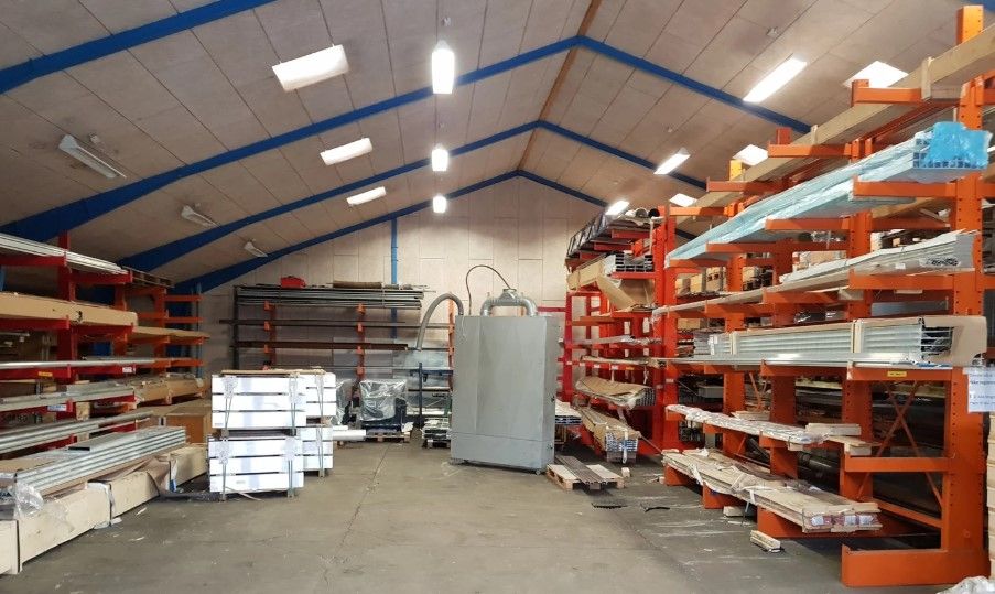 Lejlighed med masser af plads til lager med højloftede og lyse vægge, flere høje lagerreoler med mange varer og maskiner