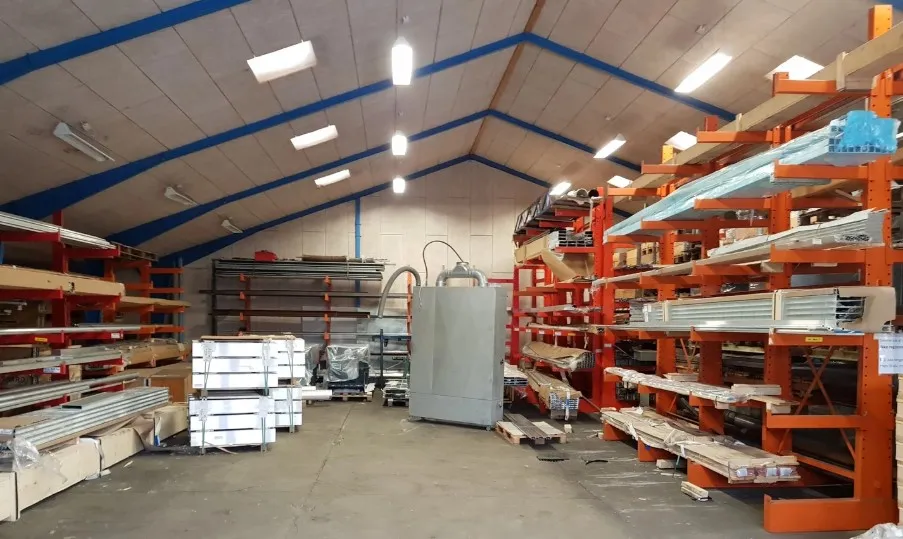 Lejlighed med masser af plads til lager med højloftede og lyse vægge, flere høje lagerreoler med mange varer og maskiner