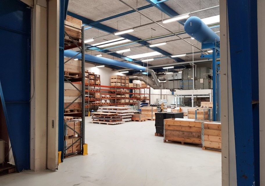 Lager med mange trækasser og træpæle samt lysekroner og ventilationsrør i loftet