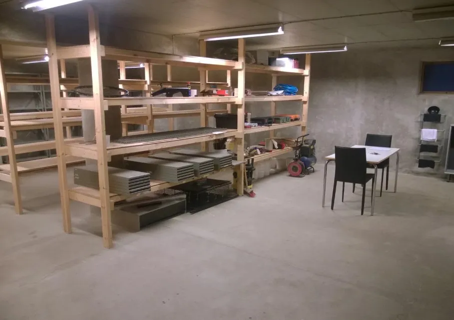 Lejlighedsvist rum med masser af plads til opbevaring af diverse ting, såsom materialer, værktøj og andet. Et bord og stole