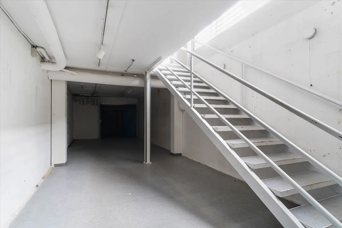 Styretræk, hvidt gulv og lyse loft, som fører op til en lys indgangsdør.