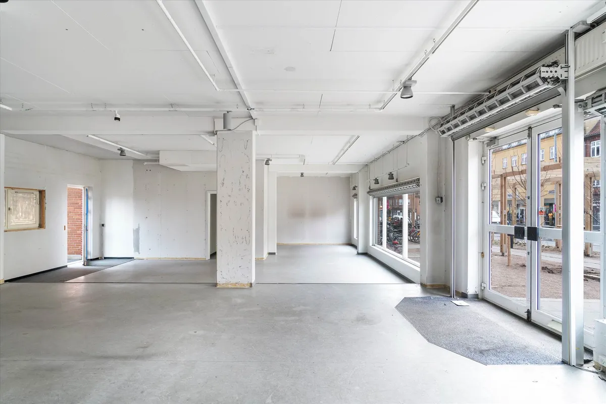 Hjørne lokale i Søborg med store vinduer og glasdøre mod gaden og højt loft. Lokalerne er uden møbler og har en simpel