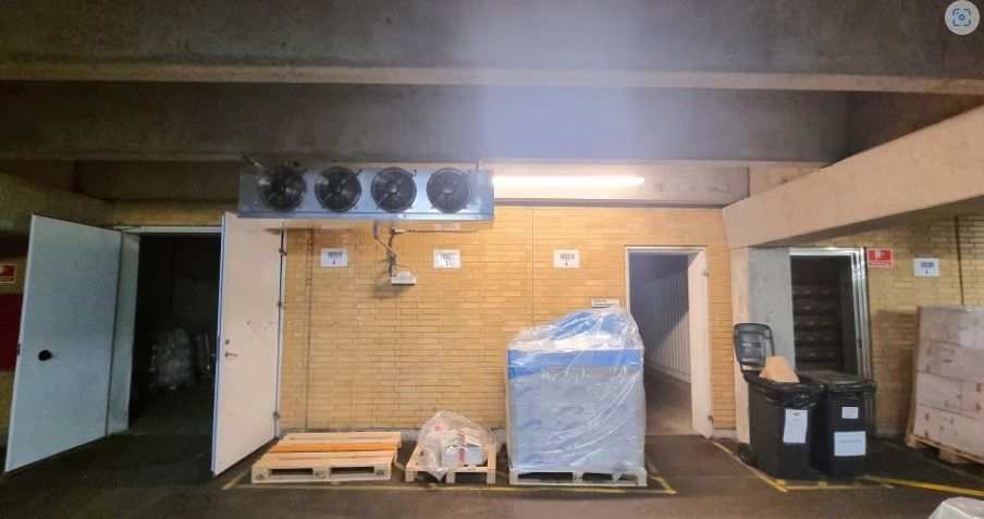 Lager med åbne døre og opbevaringsbokse, hvor køleapparater er installeret på væggen. Der er flere kasser og