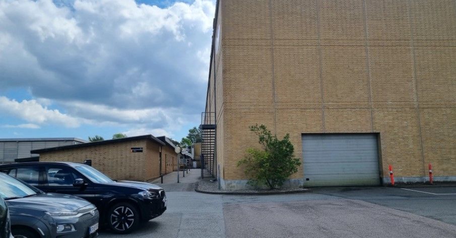 Lejemål med garage og lagerplads i Fredericia. Tre biler parkeret udenfor bygningen.