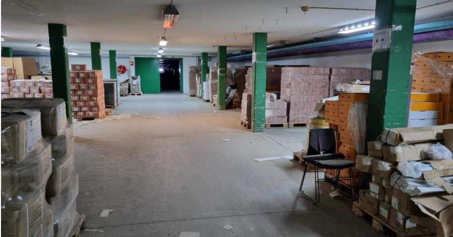 Lager med flere rækker pakketøj, der er opstillet på paller og pakket i plastikfilm. Der er to stolpetyper og flere