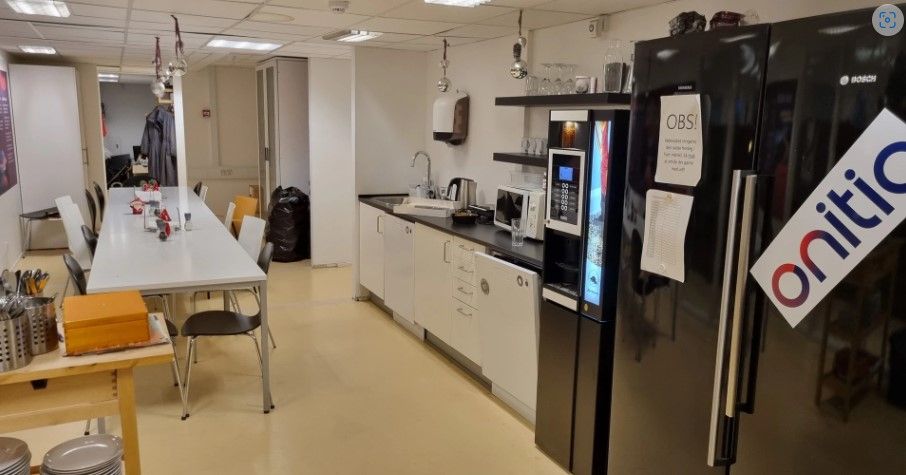 Køkken med flere stole, en lang bord, en ovn, en køleskab og en mikrobølgeovn