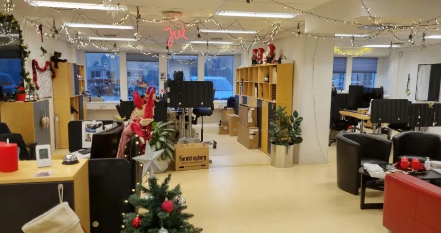 Kontor med skrivebord, sofa og ståpule. Her er også en juletræ, julepynt og en række små dekorationer.